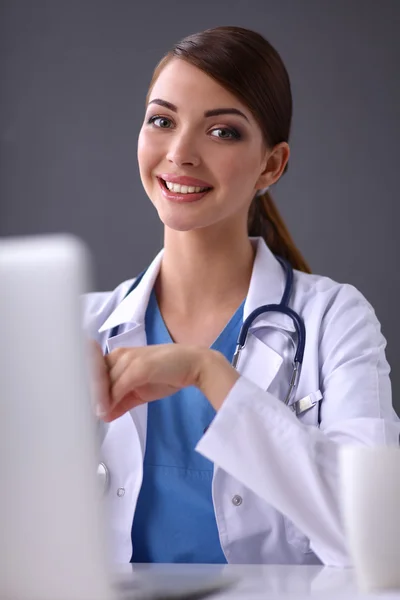 Médico femenino trabajando sentado sobre fondo gris — Foto de Stock