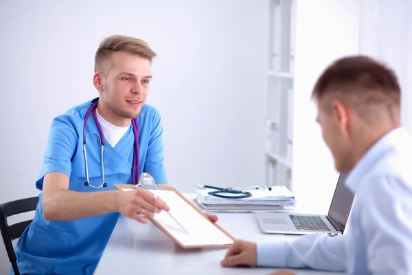 Médico macho dando pasta paciente com papel em seu escritório, isolado — Fotografia de Stock