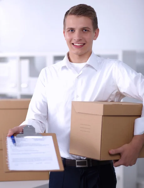 Levering man met perceel en een Tablet PC staande in office — Stockfoto