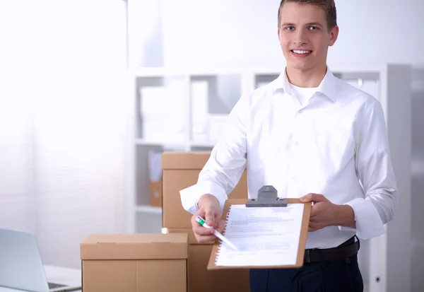 Uomo di consegna con pacco e tablet in piedi in ufficio — Foto Stock