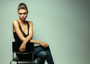 Gri arka plan üzerinde izole bir sandalye oturan güzel kadın