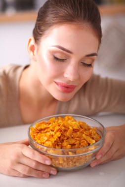 Gülümseyen çekici kadın mutfağın içinde kahvaltı yapıyor.