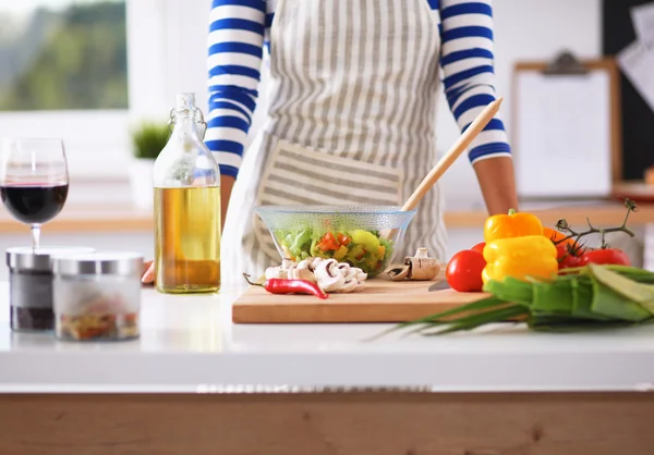 Mujer joven mezclando ensalada fresca, de pie cerca del escritorio —  Fotos de Stock