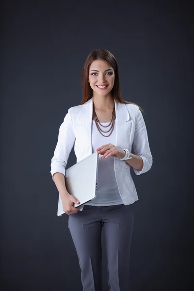 Young woman holding a laptop, standing on grey background — Stock Photo, Image
