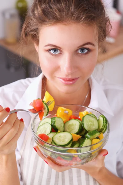 Jovem mulher comendo salada fresca na cozinha moderna — Fotografia de Stock