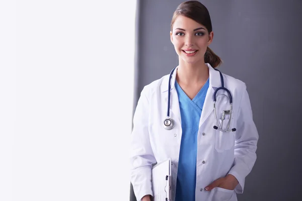 Junger Arzt oder Sanitäter mit Klemmbrett und Stethoskop isoliert auf grauem Hintergrund — Stockfoto