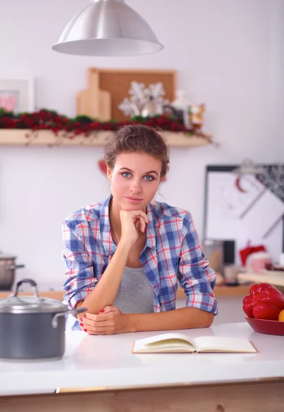 Sorridente giovane donna in cucina, isolata su sfondo natalizio — Foto Stock