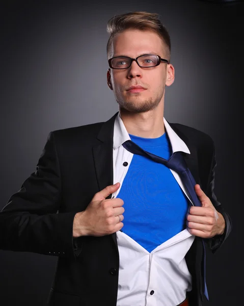 Joven hombre de negocios actuando como un súper héroe y rasgando su camisa, aislado sobre un fondo gris — Foto de Stock