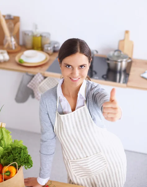 Woman in apron standing on the desk with grocery bagand showing ok — Stock Photo, Image