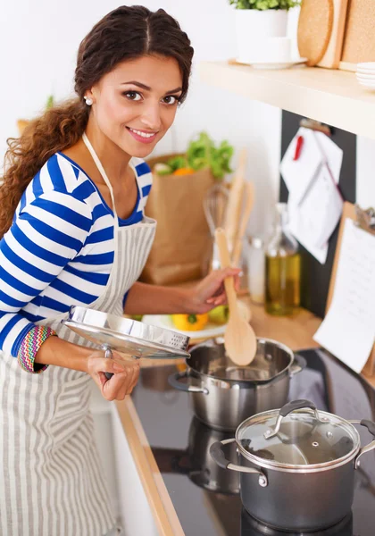 Mooie vrouw staande in keuken met schort — Stockfoto