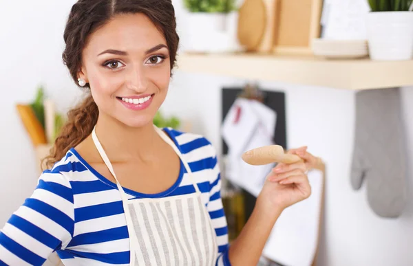 Beautiful woman standing in kitchen with apron — Stock Photo, Image