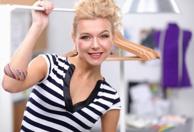 Raf ofiste askıları ile yakınındaki güzel genç stilist