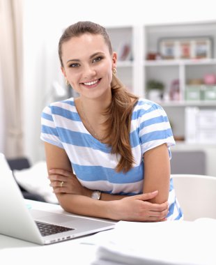 Elinde evrakları olan kadın masanın üstünde oturuyor.