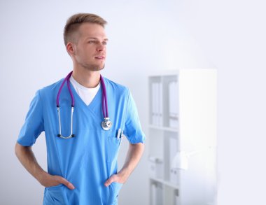 Steteskoplu doktor ayakta, çapraz kollu, beyaz arka planda izole.