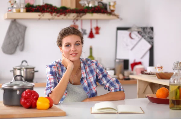 Glimlachende jonge vrouw in de keuken, geïsoleerd op kerst achtergrond — Stockfoto