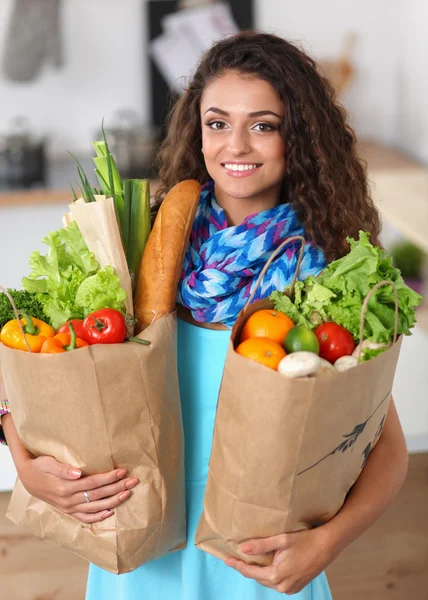 Young woman holding grocery shopping bag with vegetables Standing in the kitchen. — Stock Photo, Image