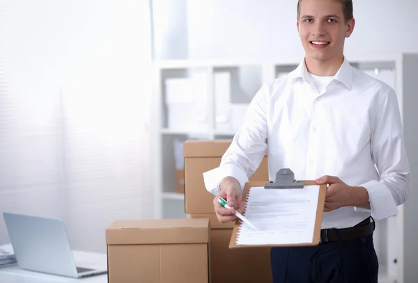 Uomo di consegna con pacco e tablet in piedi in ufficio — Foto Stock