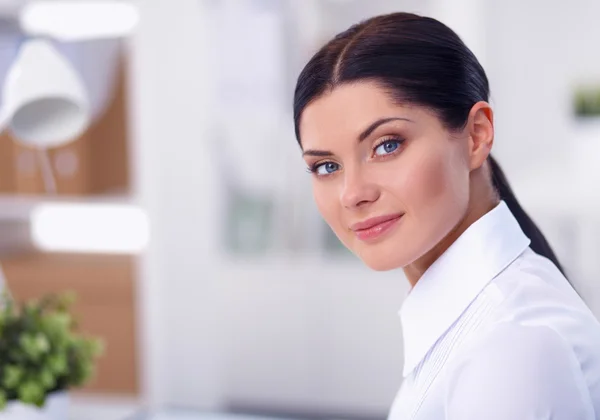 Attractive businesswoman sitting  on desk in the office — Stock Photo, Image