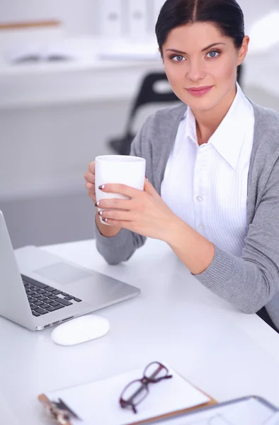 Attractive businesswoman sitting  on desk in the office — Stock Photo, Image