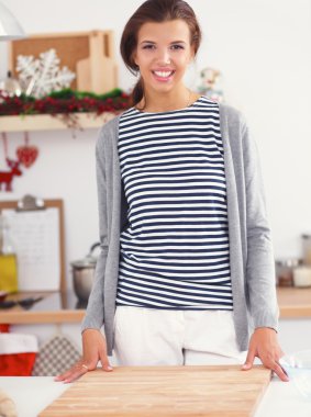 Mutfakta gülümseyen genç bir kadın, Noel arkaplanında.