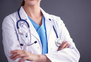 Steteskoplu doktor kadın gri duvarın yanında duruyor.