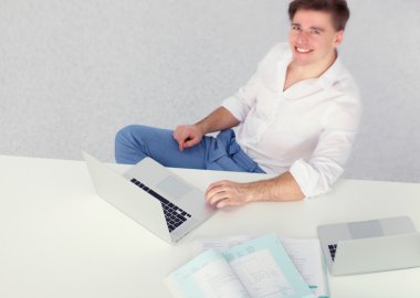 Genç işadamı ofiste çalışıyor, masada oturuyor.