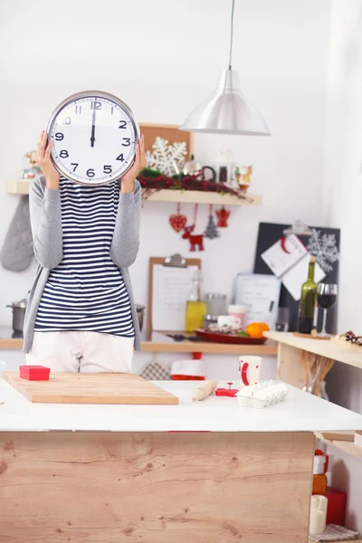 Gelukkig jong vrouw tonen klok in kerst versierd keuken — Stockfoto