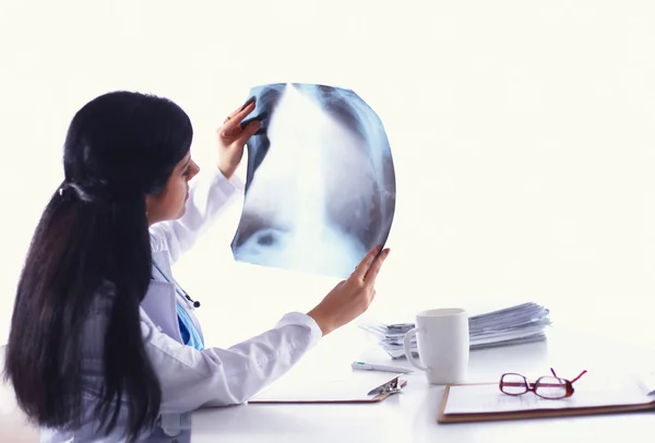 Junge Ärztin studiert Röntgenbild und sitzt am Schreibtisch — Stockfoto