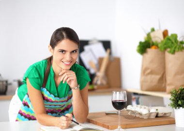 evde bir defter üzerinde yazma onu mutfakta ayakta mutlu güzel kadın