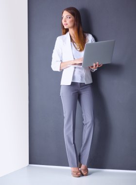 Bir dizüstü bilgisayar, gri arka plan üzerinde ayakta tutan genç kadın