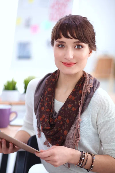 Junge attraktive Modedesignerin steht im Büro am Schreibtisch und hält Ordner in der Hand — Stockfoto