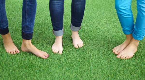 Drie vrouwen met naakt voeten permanent in gras — Stockfoto