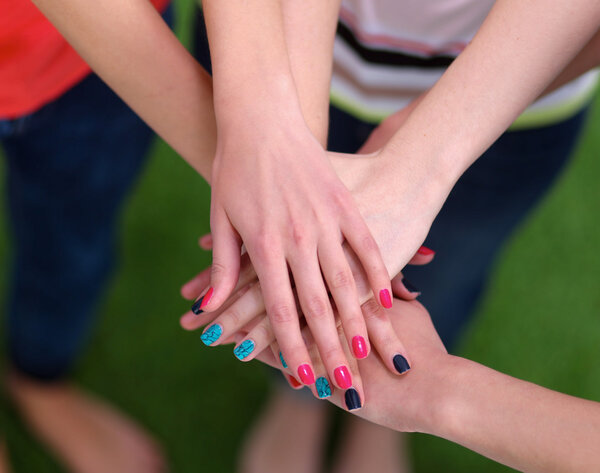 Люди, соединяющие руки на зеленой траве
