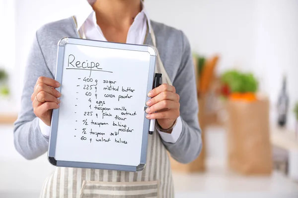 Kvinna i köket hemma, stående nära skrivbord med mapp — Stockfoto