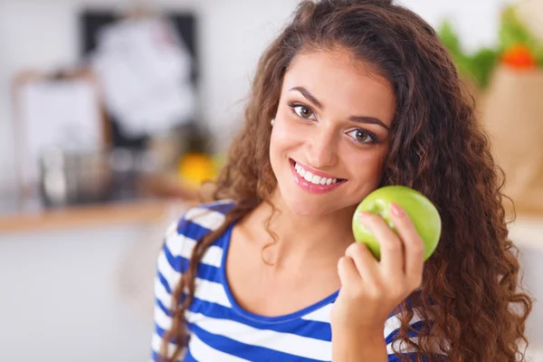 행복 한 젊은 여자가 부엌에서 사과를 먹다 — 스톡 사진