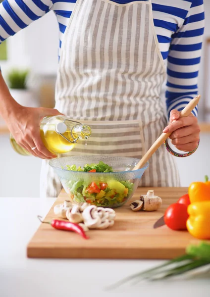 Jonge vrouw mengt verse salade — Stockfoto