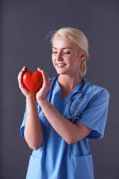 Doctor with stethoscope holding heart, isolated on gray background — Stock Photo, Image