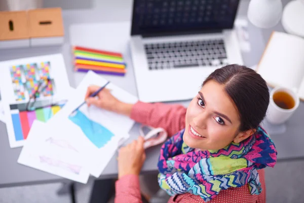 Jonge aantrekkelijke vrouwelijke mode-ontwerper werken op kantoor bureau, tekenen terwijl het praten op mobiele — Stockfoto