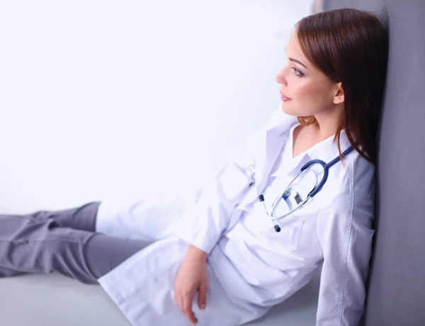 Mladá žena lékař sedí na podlaze — Stock fotografie