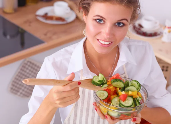 Jovem mulher comendo salada fresca na cozinha moderna — Fotografia de Stock