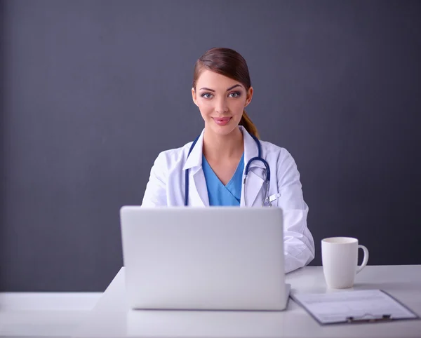 Femme médecin travaillant assis sur fond gris — Photo