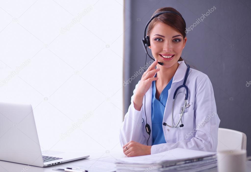 Doctor wearing headset sitting behind a desk with laptop