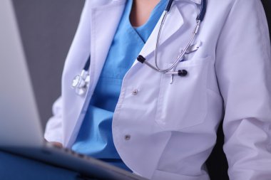 Gri arka planda oturan kadın doktor