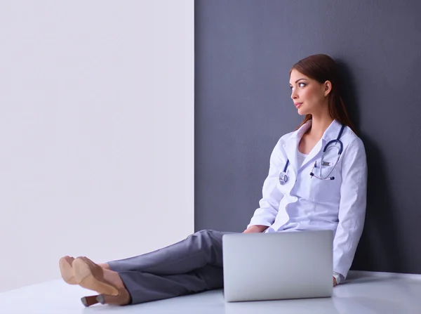 Doctor sitting  the floor near wall  with laptop — Stock Photo, Image