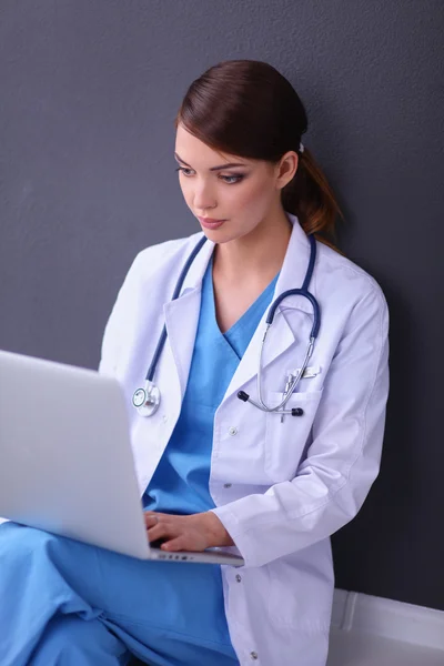 Médico femenino trabajando sentado sobre fondo gris — Foto de Stock