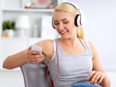 Evdeki genç ve güzel kadın kanepede oturup müzik dinliyor.