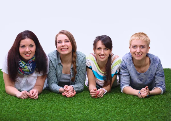 Four young women lying on green grass — Stock Photo, Image