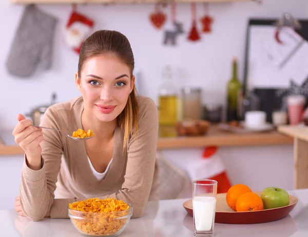Uśmiechnięta atrakcyjna kobieta je śniadanie we wnętrzu kuchni — Zdjęcie stockowe