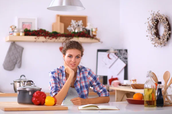 Glimlachende jonge vrouw in de keuken, geïsoleerd op kerst achtergrond — Stockfoto