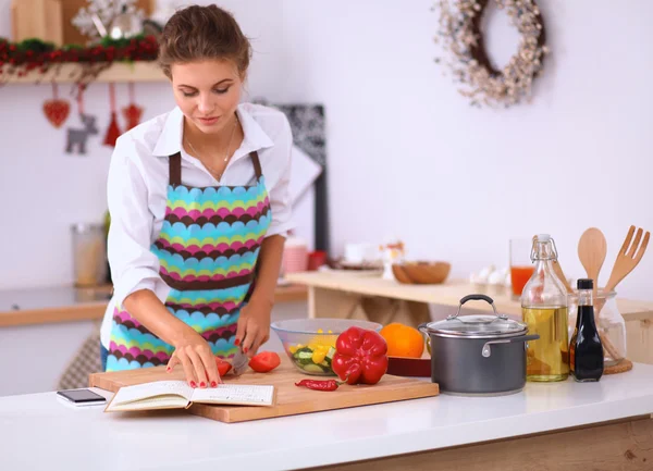 Mulher jovem cortando legumes na cozinha — Fotografia de Stock